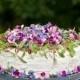 White wedding cake decorated with pink and purple petals