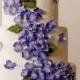Wedding cake with purple colored blossoms.
