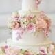 Wedding Cake with light colored blossoms all around.