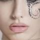 Makeup with black-colored swirls and rhinestone at the corner.
