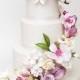 Stunning Sugar Flowers And Colorful Butterflies Are Fabulous Against An All-white Wedding Cake.
