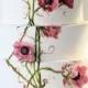 A Four-tiered Wedding Cake Features Hand-painted Flowers And Vines, As Well As Pink Sugar Anemones.