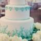 The Three-tier Wedding Cake Is Decorated With Turquoise Swags And Topped With Sugar Coral.