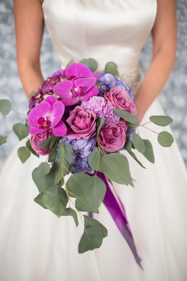 Wedding - Gorgeous bride holding radiant purple and blue colored blossoms.