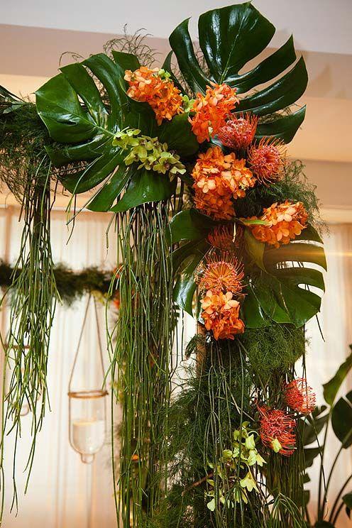 Wedding - Orange And Green Orchids, Banana Leaves And Pincushion Proteas Are Draped Over The Pillars Of This Tropical-themed Altar.