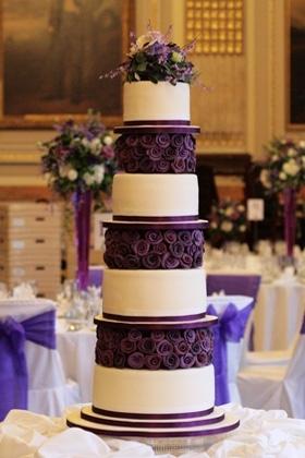 Wedding - Layers Of Deep Purple Fondant Roses Contrast Against Tiers Of Sleek White Cake.