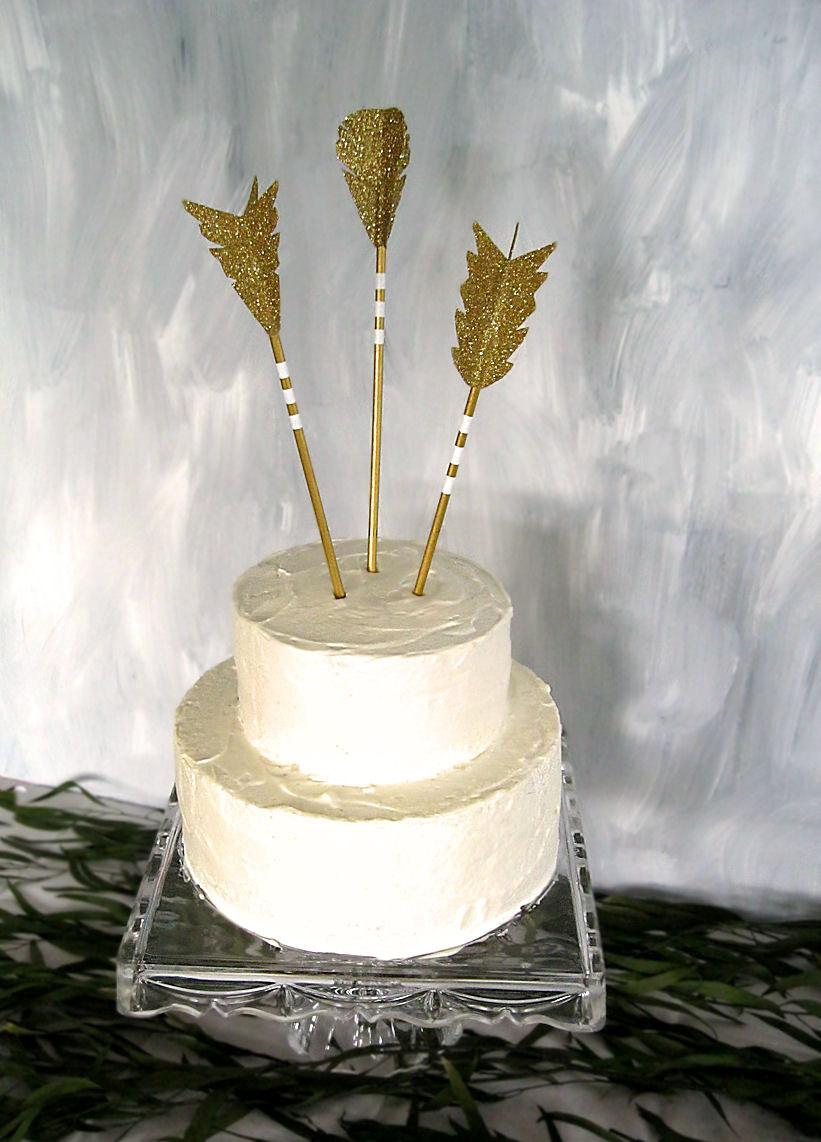 Wedding - The Archer arrow cake topper decoration shown in gold and white with glitter