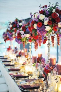 wedding photo - Opulent Centerpieces Of Red, White And Purple Roses, Purple Hydrangeas And Dangling Grapes Make A Bold Statement.