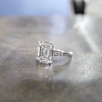 HALLE Is A Custom, Three Stones Engagement Ring Set In Platinum With An Emerald Cut Diamond And Two Tapered Baguettes, From Jewelry D… wedding photo - HALLE Is A Custom, Three Stones Engagement Ring Set In Platinum With An Emerald Cut Diamond And Two Tapered Baguettes, From Jewelry D…
